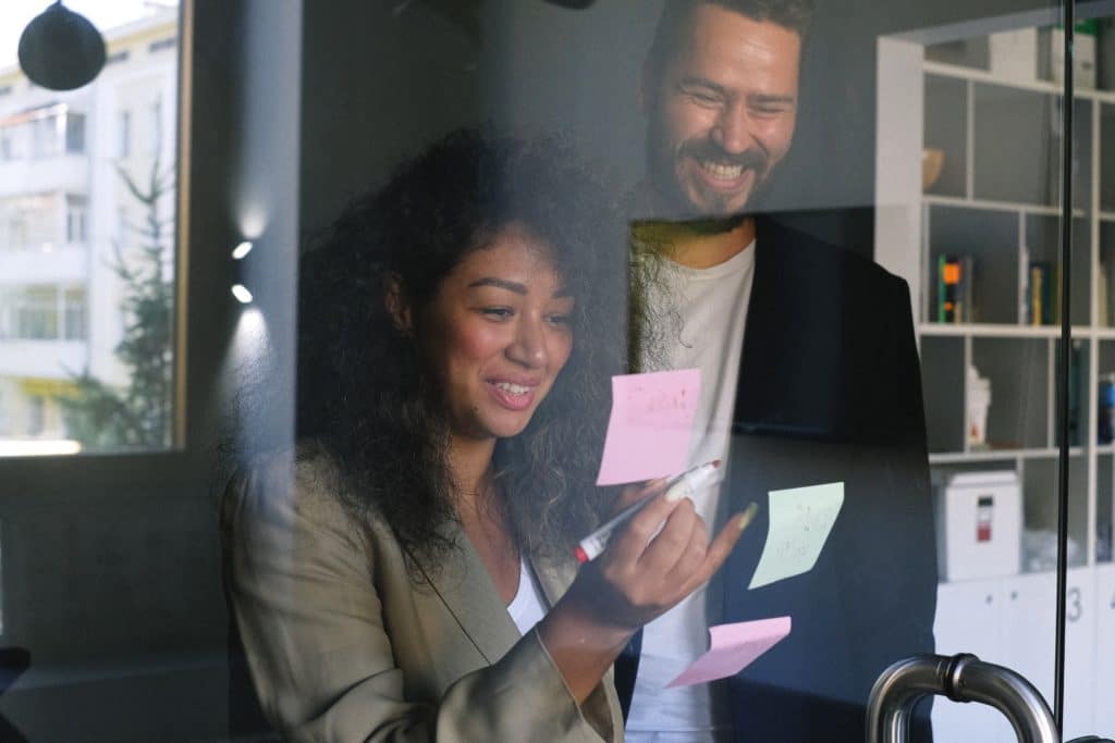 photo of man and woman in an office with sticky notes on glass door